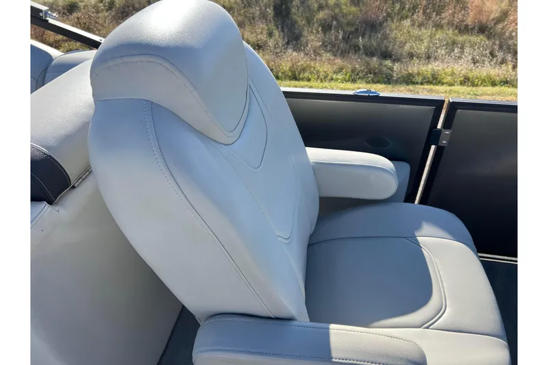 Slide: The Image of 2022 Sylvan Mirage X1 Tritoon boat seat with armrest, featuring light gray upholstery. - 34