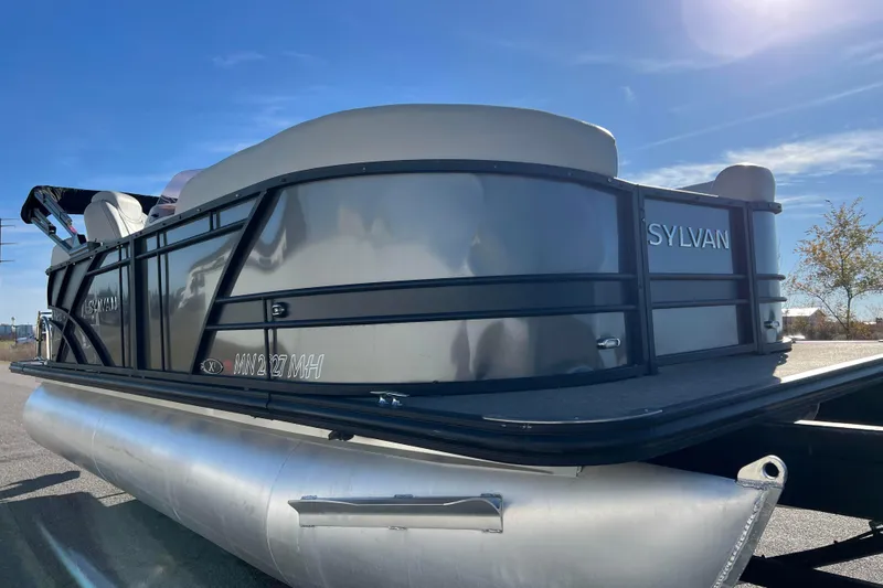 Slide: The Image of 2022 Sylvan Mirage X1 Tritoon boat on a sunny day, showcasing sleek design and pontoon structure. - 5