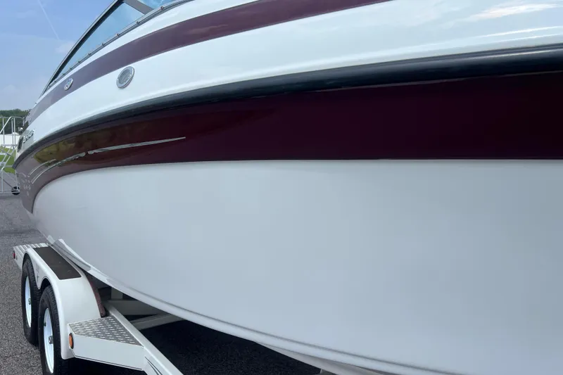 Slide: The Image of 2003 Crownline 230 BR boat on trailer, featuring sleek maroon and white design. - 10