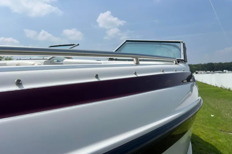 Slide: The Image of 2003 Crownline 230 BR boat, sleek design, sunny day, grassy background. - 26