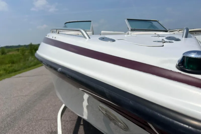 Slide: The Image of 2003 Crownline 230 BR boat, white with maroon stripe, parked on a sunny day. - 28