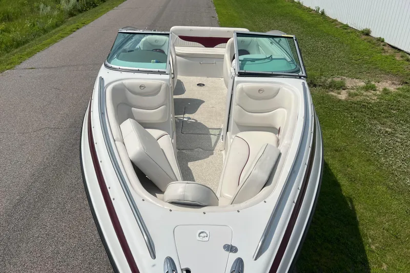 Slide: The Image of 2003 Crownline 230 BR boat with white interior, parked on a paved road. - 3