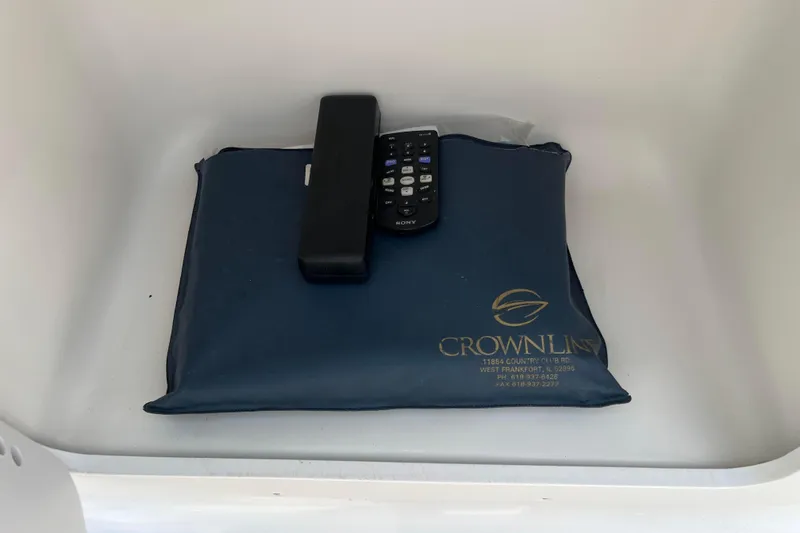 Slide: The Image of Remote controls on a blue Crownline pouch inside a 2003 Crownline 230 BR boat compartment. - 43