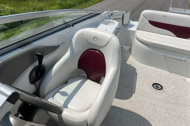 Slide: The Image of 2003 Crownline 230 BR boat interior with white and maroon seating, steering wheel, and controls. - 60