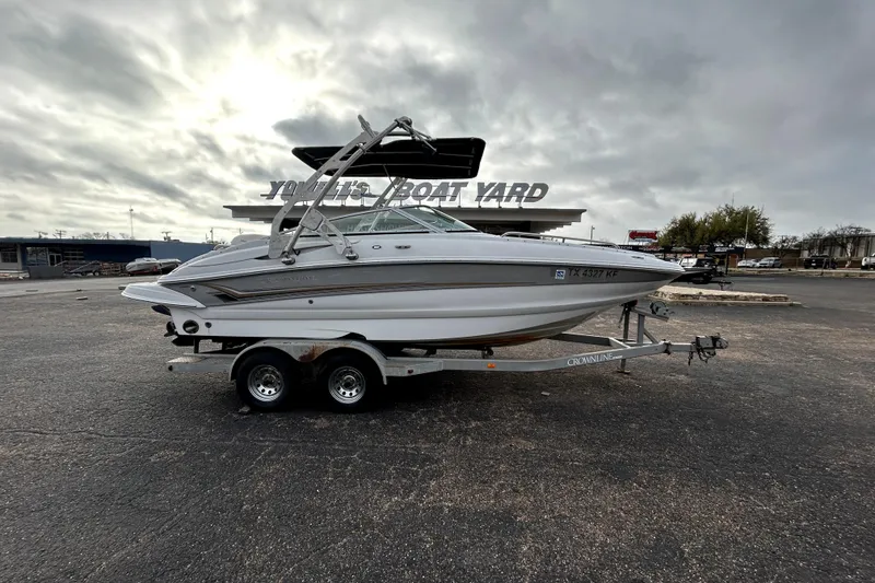 The Image of 2005 Crownline 220 LS boat on trailer at a boat yard under cloudy skies. - 0