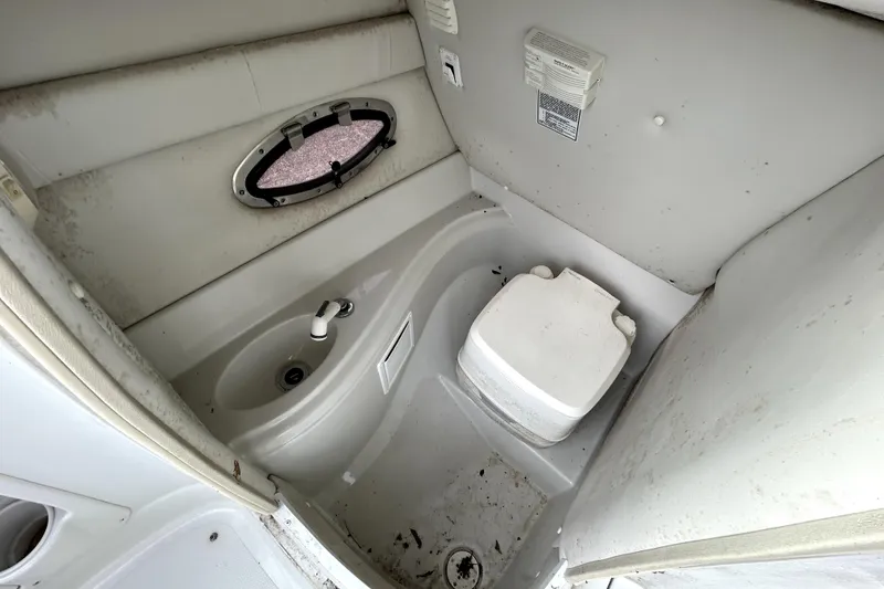 Slide: The Image of 2005 Crownline 220 LS boat bathroom with sink and toilet, featuring a small window. - 22