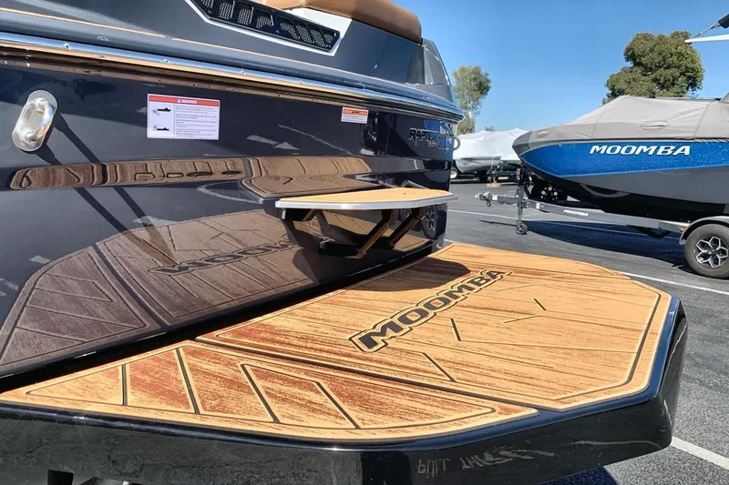 Slide: The Image of 2026 Moomba Max boat with wooden deck and sleek design in a parking lot. - 21