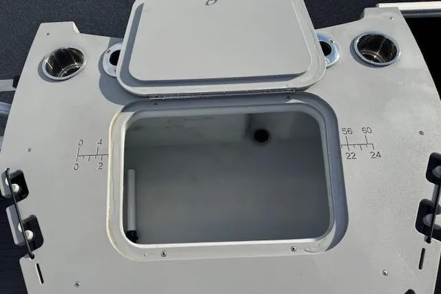 Slide: The Image of Open storage compartment on 2022 Bennington S 18 Fishing boat with cup holders and measurement markings. - 16