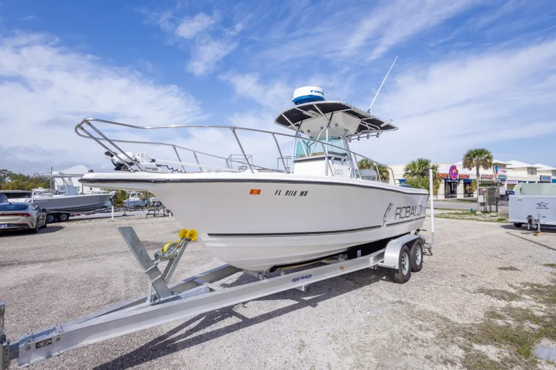Slide: The Image of 1997 Robalo R230 Center Console boat on trailer, parked outdoors under blue sky. - 11