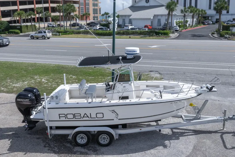 Slide: The Image of 1997 Robalo R230 Center Console boat on trailer, parked near a road. - 14