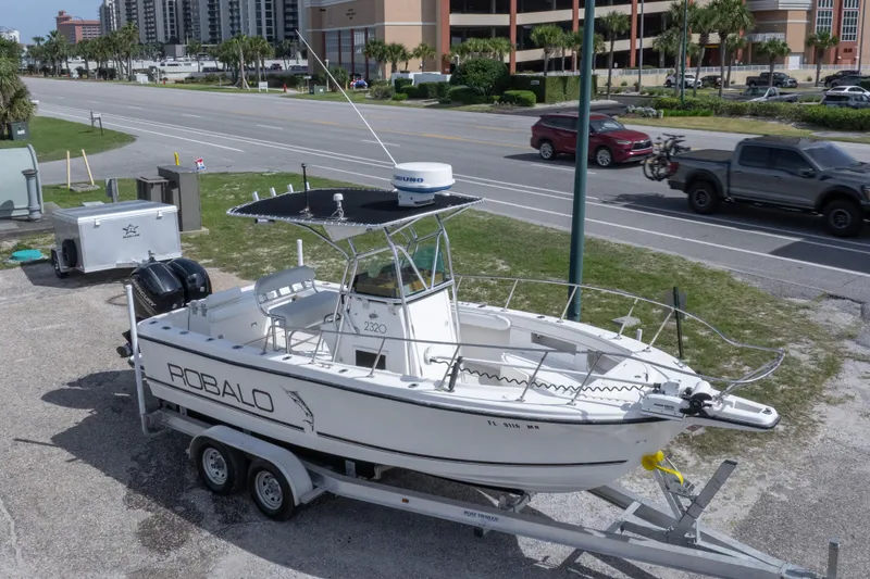 Slide: The Image of 1997 Robalo R230 Center Console boat on trailer, parked near a road. - 9
