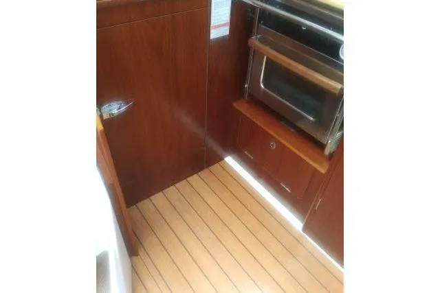Slide: The Image of Interior of 2005 Beneteau 393 yacht showing wooden cabinetry and built-in oven. - 10