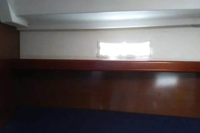 Slide: The Image of Interior cabin view of a 2005 Beneteau 393 sailboat, featuring wooden paneling and a small window. - 12