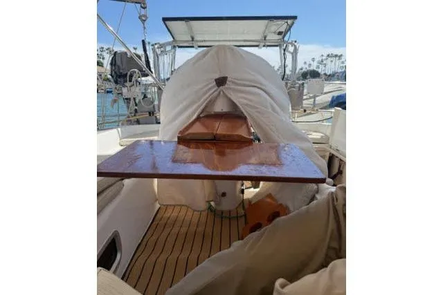 Slide: The Image of 2005 Beneteau 393 sailboat cockpit with wooden table and covered equipment. - 31