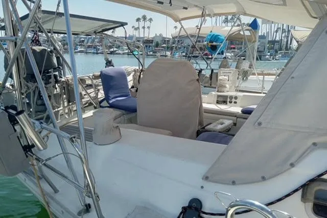 Slide: The Image of 2005 Beneteau 393 sailboat cockpit with marina view, featuring covered seating and nautical equipment. - 34
