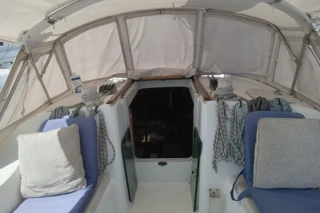 Slide: The Image of Cockpit of 2005 Beneteau 393 sailboat with cushions and ropes under canopy. - 35