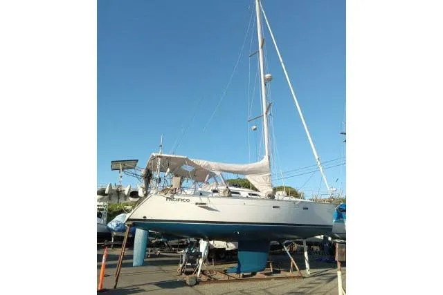 Slide: The Image of 2005 Beneteau 393 sailboat on dry dock, white hull, blue keel, clear sky. - 46