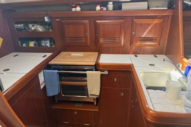 Slide: The Image of 2005 Beneteau 393 yacht kitchen with wooden cabinets, stove, and sink. - 7