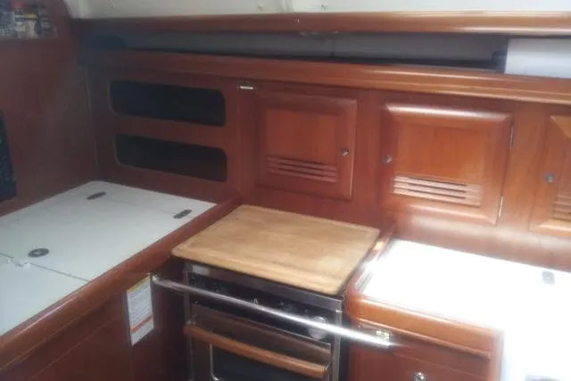 Slide: The Image of 2005 Beneteau 393 yacht kitchen with wooden cabinets and stove. - 8