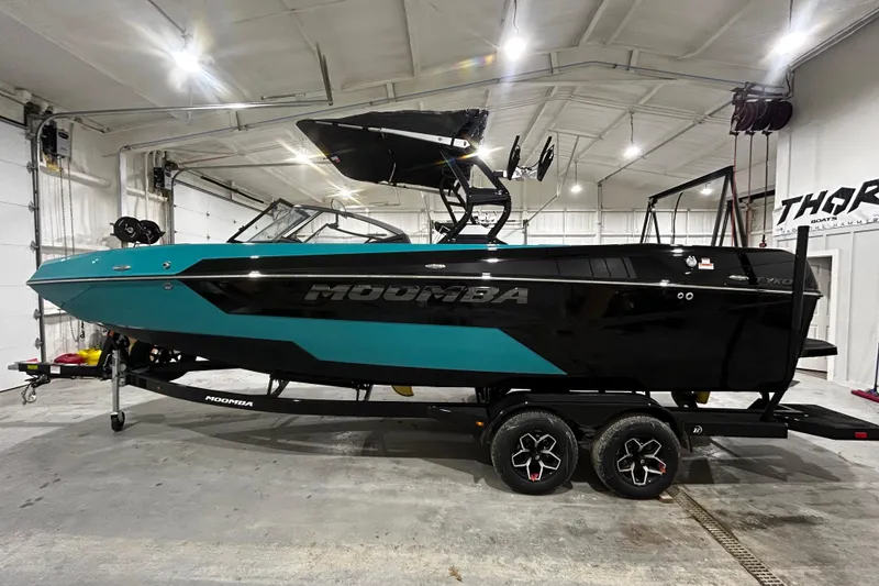 The Image of 2026 Moomba Tykon boat in a garage, featuring a sleek black and teal design. - 0