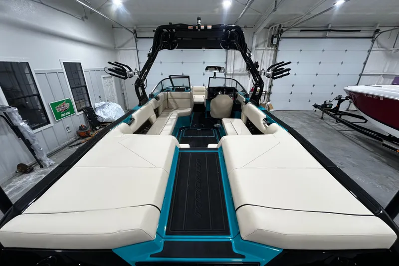 Slide: The Image of 2026 Moomba Tykon boat interior with beige seating and teal accents in a garage setting. - 3