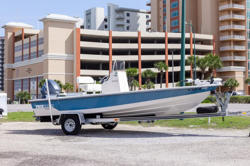 The Image of 2007 Pathfinder 2000 V boat on trailer, parked near modern buildings. - 0