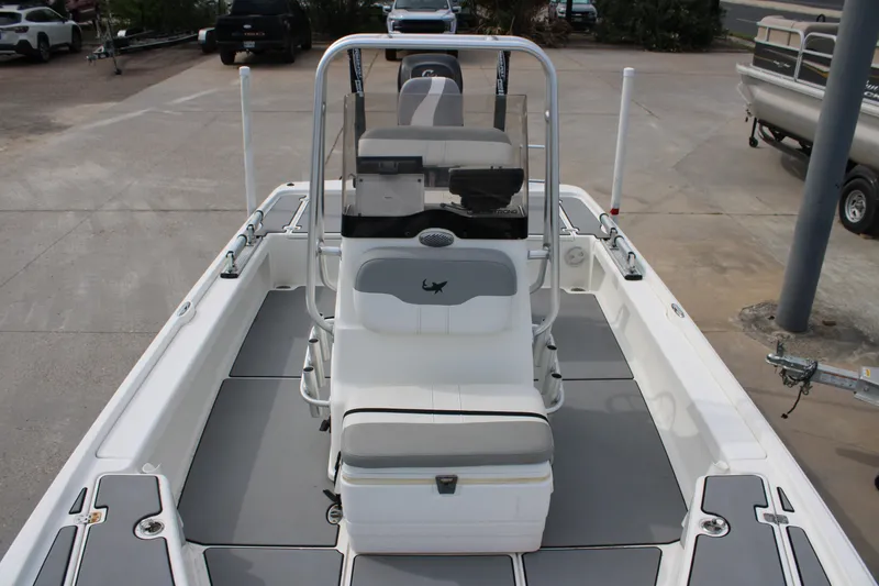 Slide: The Image of 2018 Mako 21 LTS boat interior with seating and console, parked on concrete. - 13