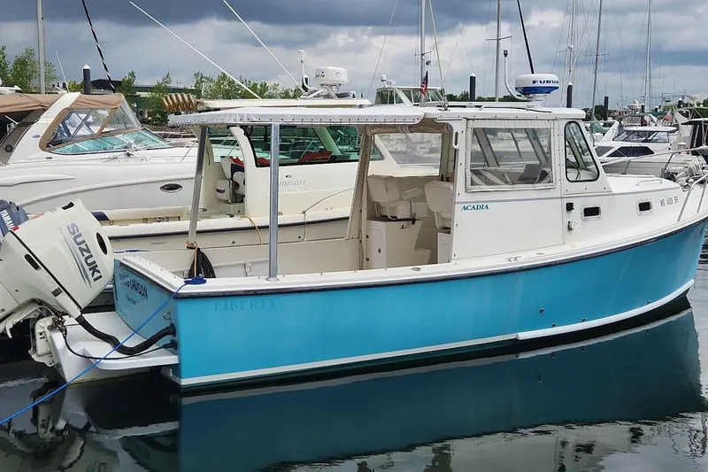The Image of 2018 Acadia Atlas boat docked, featuring a blue hull and Suzuki outboard motor. - 0