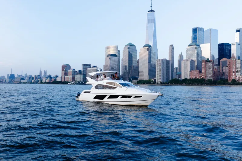 Slide: The Image of 2016 Sunseeker Manhattan 65 yacht cruising near a city skyline on a clear day. - 57