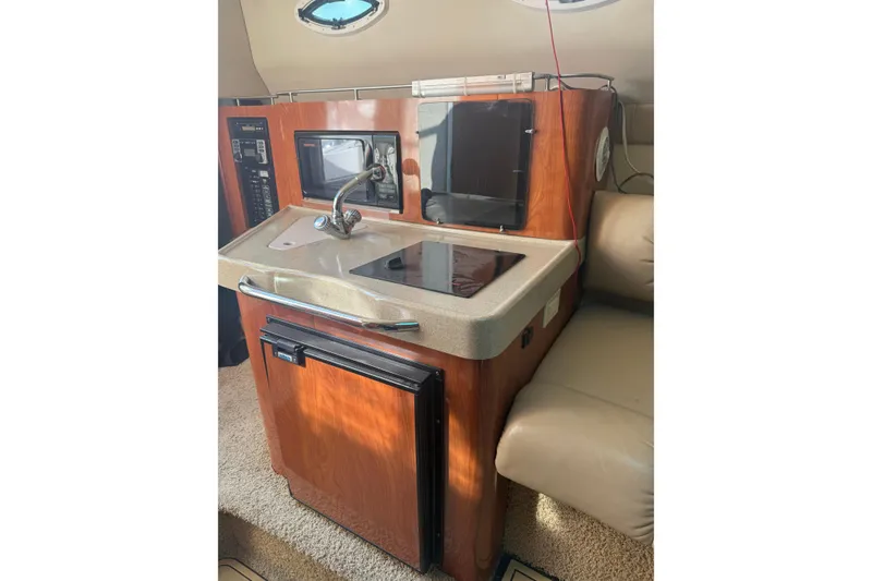 Slide: The Image of 2007 Larson Cabrio 260 boat interior with kitchenette, featuring sink, stove, and microwave. - 13