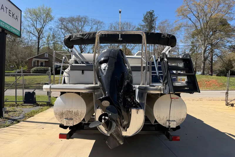 Slide: The Image of 2025 Harris Sunliner 230 pontoon boat with outboard motor, parked outdoors. - 2