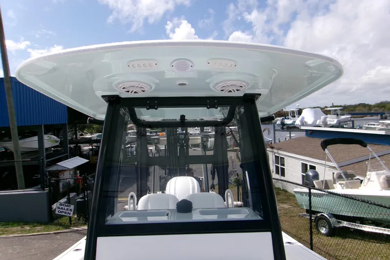 Slide: The Image of 2026 Sportsman Open 232 Center Console boat with T-top and speakers, docked under blue sky. - 15