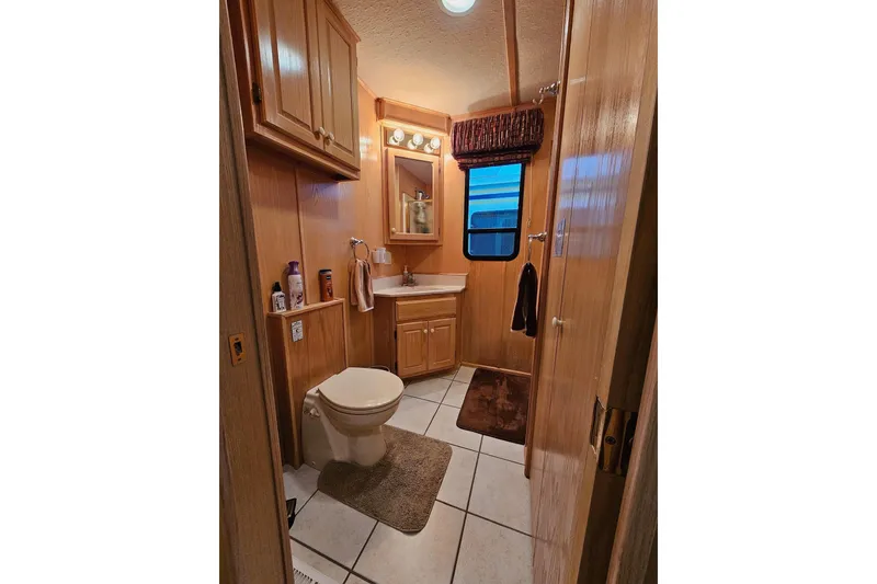 Slide: The Image of Bathroom interior of 2002 Lakeview 16x60 houseboat with wooden cabinets and tiled floor. - 27