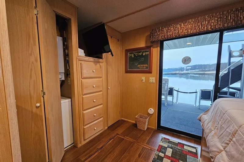 Slide: The Image of Cozy Lakeview 16x60 houseboat interior with wood paneling, TV, and scenic water view. - 40