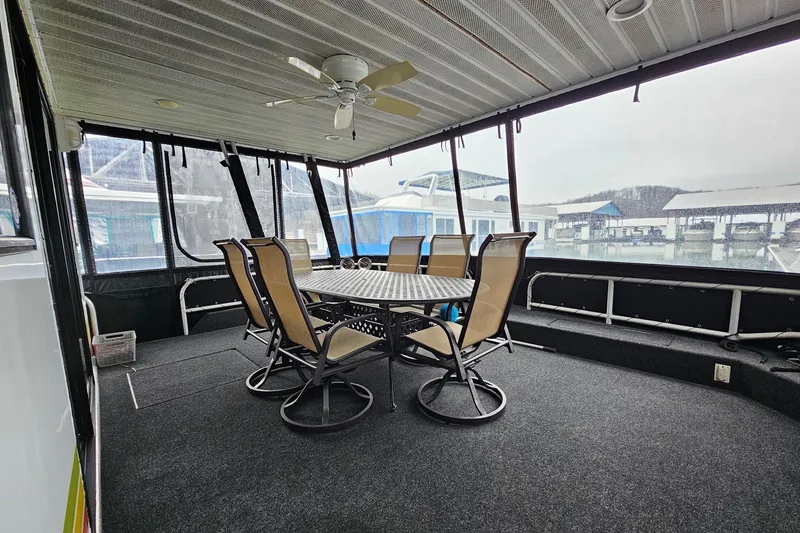 Slide: The Image of Covered deck area on a 2002 Lakeview 16x60 houseboat with dining table and chairs. - 6
