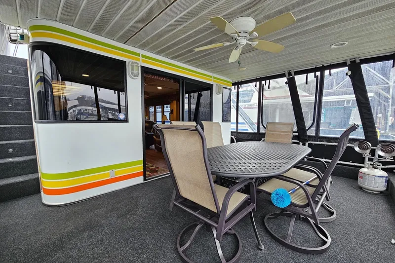 Slide: The Image of 2002 Lakeview 16x60 houseboat interior with dining area, ceiling fan, and outdoor seating. - 7