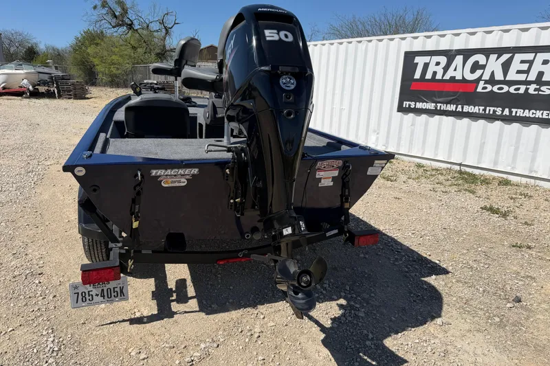 Slide: The Image of 2021 Tracker Pro 170 boat with Mercury 50 engine, parked on gravel near Tracker Boats sign. - 2