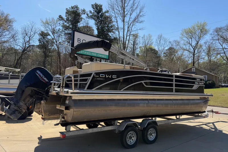 Slide: The Image of 2024 Lowe SS 230 pontoon boat on trailer, featuring Mercury outboard motor. - 2