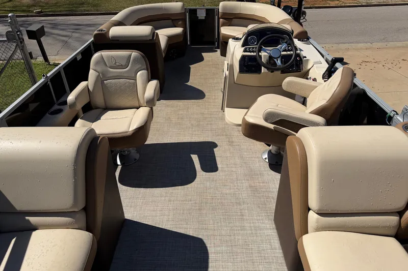 Slide: The Image of 2024 Lowe SS 230 pontoon boat interior with beige seating and steering console. - 3