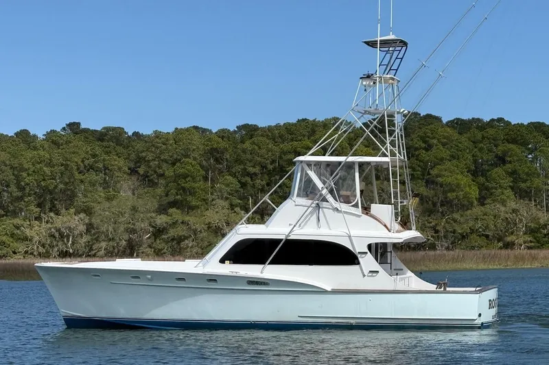 The Image of 1963 Rybovich 45 Convertible yacht on calm water, surrounded by lush greenery. - 0