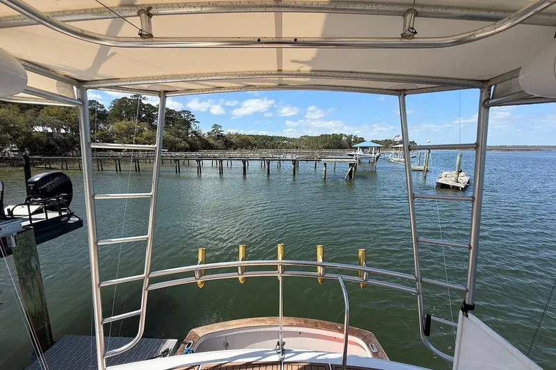 Slide: The Image of 1963 Rybovich 45 Convertible boat view, docked near a scenic waterfront with clear skies. - 15