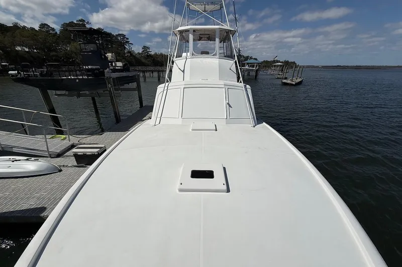 Slide: The Image of 1963 Rybovich 45 Convertible yacht docked by the water under a partly cloudy sky. - 23