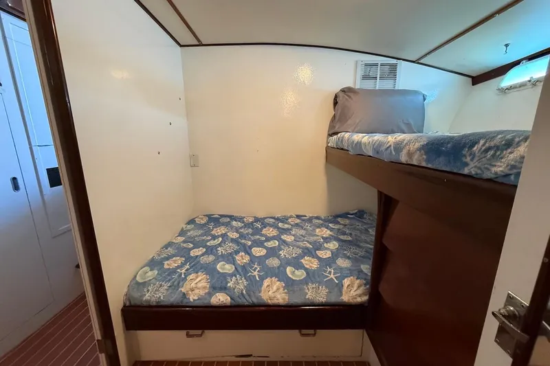 Slide: The Image of 1963 Rybovich 45 Convertible cabin with bunk beds and nautical-themed bedding. - 47