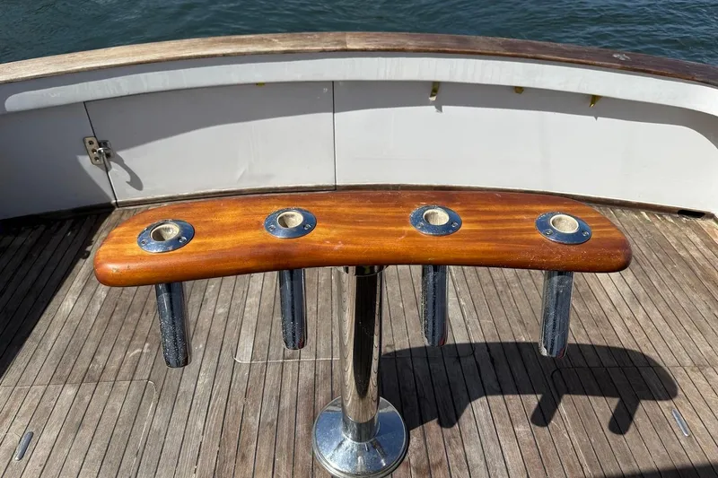 Slide: The Image of 1963 Rybovich 45 Convertible fishing rod holder on wooden deck, ocean backdrop. - 9