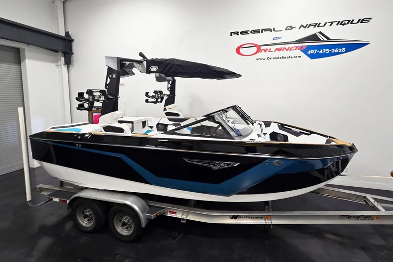 The Image of 2026 Nautique Super Air Nautique S21 boat on trailer in showroom. - 1