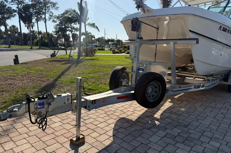 Slide: The Image of 2014 Carolina Cat 23DC boat on trailer, parked on brick driveway, surrounded by palm trees. - 11
