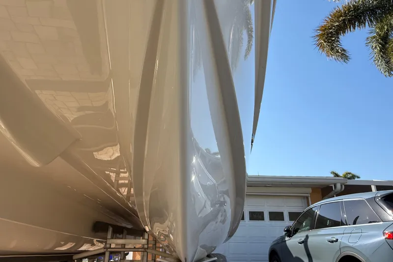 Slide: The Image of 2014 Carolina Cat 23DC boat hull beside a parked car under a clear blue sky. - 13