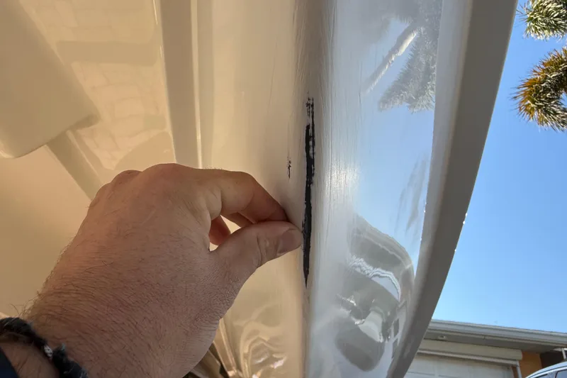 Slide: The Image of Hand inspecting damage on 2014 Carolina Cat 23DC boat hull. - 14