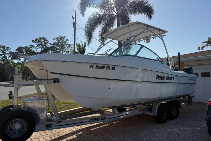 Slide: The Image of 2014 Carolina Cat 23DC boat on trailer, parked in driveway with palm trees in background. - 2