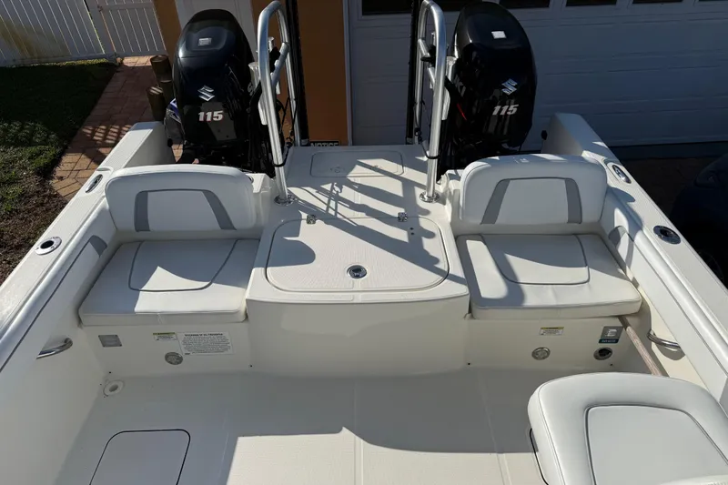 Slide: The Image of 2014 Carolina Cat 23DC boat interior with dual Suzuki 115 engines, white seating, and storage compartments. - 20
